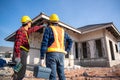 Contractor and worker holding electrician toolbox at unfinished house at construction site. Teamwork concept Royalty Free Stock Photo