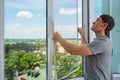 A contractor worker installing mosquito wire screen on house plastic windows to protect from insects.