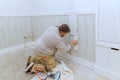 Contractor worker nailing wooden trim moldings at a room