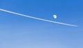 Contrail white trail in a bright blue sky leaves a jet plane.Moon