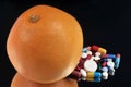 Grapefruit next to an assortment of drugs on a black background Royalty Free Stock Photo