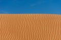 Contrast beautiful deep blue sky and orange rippled pattern sand dunes in the United Arab Emirates.