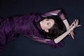 Contrast fashion Armenian woman portrait with big blue eyes lying on the floor in a purple dress. Lovely gorgeous girl posing Royalty Free Stock Photo