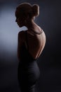 Contrast fashion woman portrait on dark background, the silhouette of a girl with a beautiful curved back. Naked back of a woman