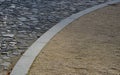 Contrast between gray basalt paving for cars and soft gravel road for pedestrians made of beige sandy material. the transition con