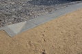 Contrast between gray basalt paving for cars and soft gravel road for pedestrians made of beige sandy material. the transition con