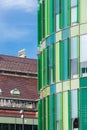 Contrast between a green glass facade of a modern building in front of another traditional old building Royalty Free Stock Photo