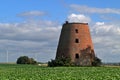 Old ruined abandoned windmill tower with electric power plant in the background Royalty Free Stock Photo