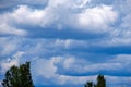 Contrast rain storm clouds over green meadow and some trees in summer. blue sky before the rain Royalty Free Stock Photo