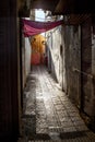 Contrast Sale Morocco. The narrow street of the old city and the old, chipped walls of houses under a red canopy in the summer