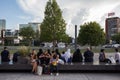 Contrast between three european girls, friends, sitting in short and summer clothing while a group of muslim women is sat behind