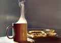 Contrasted steam from a mug containing a hot drink illuminated by the morning light and tray of small thyme mankouchi in Lebanon