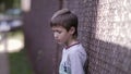 Contrasting Emotions: Sad Boy Stands on the Street and Gazes into the Camera, Remorseful Troublemaker Regrets His