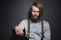 Contrasting low key portrait of a bearded long-haired stylish brutal man in a gray shirt with suspenders sternly looks