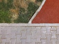 A contrasting view of green grass, withering turf, a red athletic track, and grey paving stones, depicting varied textures Royalty Free Stock Photo