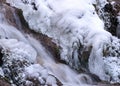 Contrasts of frozen and running water, spring water flows over pieces of limestone, running water freezes to form various Royalty Free Stock Photo