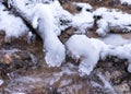 Contrasts of frozen and running water, spring water flows over pieces of limestone, running water freezes to form various Royalty Free Stock Photo