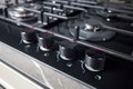 Control knobs with auto ignition selective focus closeup over out of focus black tempered glass gas stove cooker hob Royalty Free Stock Photo