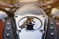 Control panel of classic orange motorcycle with lots of chrome parts and riveted tie, made of genuine brown leather. Keys are in