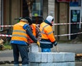 Contruction workers wearing reflective vest preparing for work for repairing street curbs. Bucharest, Romania, 2020