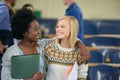 Conversation, hugging and women students in classroom with text books and documents for information. Smile, discussion Royalty Free Stock Photo