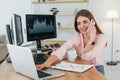 Conversation by the phone. Female stockbroker in casual clothes is working in the office by pc Royalty Free Stock Photo