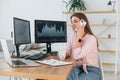 Conversation by the phone. Female stockbroker in casual clothes is working in the office by pc Royalty Free Stock Photo