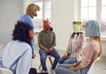 Conversation of young people in rubber masks on their heads during support group meeting.