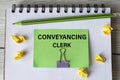 CONVEYANCING CLERK - words on a green sheet on a white notebook with a pencil and small pieces of paper