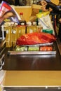 Conveyer belt filled with food at grocery market with sacks being filled up and unidentifiable customers getting ready to pay