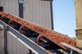 Conveyor belt transporting mulch at a landscaping supply facility on a sunny day Royalty Free Stock Photo