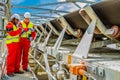 Conveyor belt transporting Platinum ore for processing with mining safety inspectors checking for damage