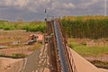 Conveyor belts and sand heaps. Construction industry. Sand quarry, heavy duty machinery. Horizontal photo.