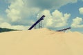 Conveyor belts and sand heaps. Construction industry. Sand quarry. Horizontal photo. Cross process effect.