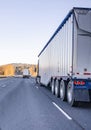 Convoy of big rigs semi trucks with different semi trailers driving on wide multiline straight highway Royalty Free Stock Photo
