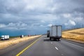 Convoy of big rigs semi trucks with trailers in both directions Royalty Free Stock Photo