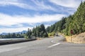 Convoy of big rigs semi trucks with semi trailers transporting cargo running downhill on the road along the Columbia River Royalty Free Stock Photo