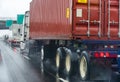 Convoy of different big rig semi truck with commercial cargo in semi trailers and container running on the wet raining highway