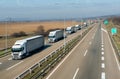 Convoy of White transportation trucks in line on a countryside highway