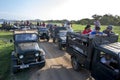 A convoy of safari jeeps carrying tourists parked adjacent to the tank at Minneriya National Park in Sri Lanka.