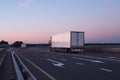 A convoy of trucks trucks transports the cargo in the evening on the highway, the concept of logistics and freight, copy