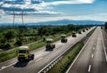 Convoy of yellow transportation semi trucks in line on a countryside highway