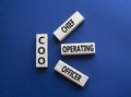 COO - Chief Operating Officer symbol. Concept word COO on wooden blocks. Beautiful deep blue background. Business and COO concept