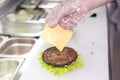 Cook adding a slice of cheese on burger Royalty Free Stock Photo