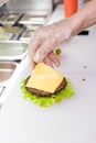 Cook adding a slice of cheese on burger Royalty Free Stock Photo