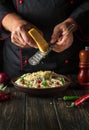 The cook adds hard cheese to spaghetti with spices in a plate. Menu or recipe for a delicious lunch for a hotel or restaurant Royalty Free Stock Photo