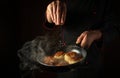 The cook adds salt to oladki in a frying pan. The concept of preparing a delicious Ukrainian national dish or bliny in the kitchen