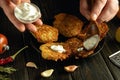 The cook adds sour cream to the potato pancakes with a spoon. Low key concept of serving a delicious vegetable dish for lunch