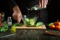 The cook adds vegetable oil for taste to the salad of all fresh cucumbers. The idea of preparing a cucumber diet on the kitchen Royalty Free Stock Photo