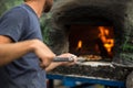 Cook baking pizza in a traditional stone oven